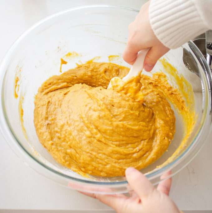 Gently mixing the pumpkin batter with a spatula.