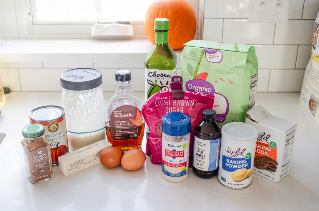 All of the ingredients needed for sourdough pumpkin bread laid out on a white countertop with a window in the background. 