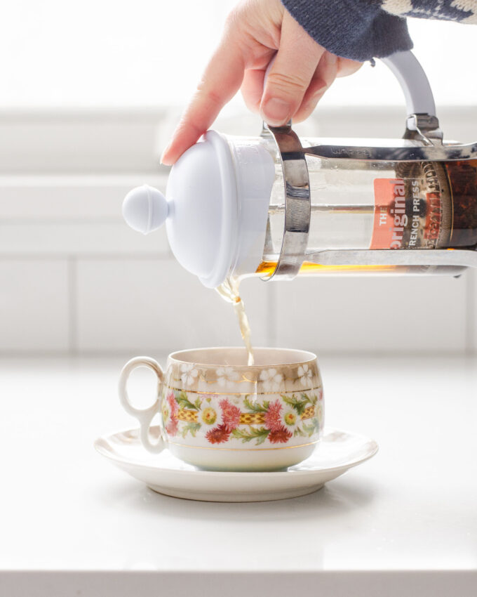 Pouring tea from a French press into a teacup.