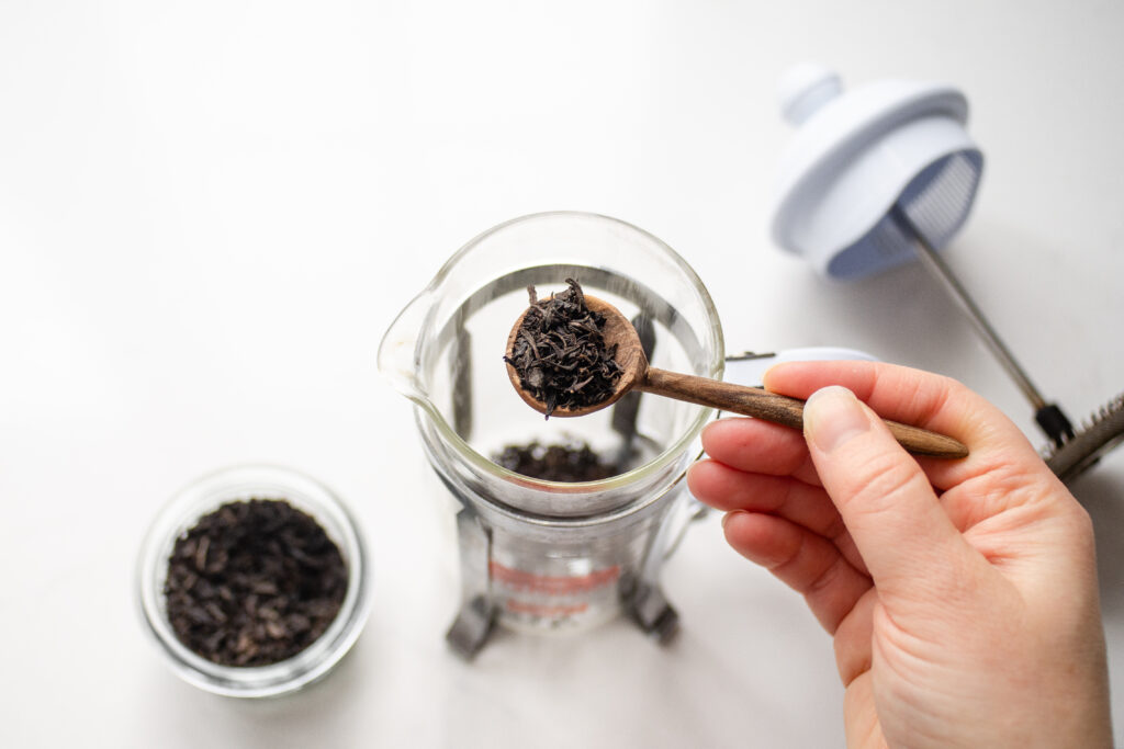 Adding a scoop of black tea to the French press.