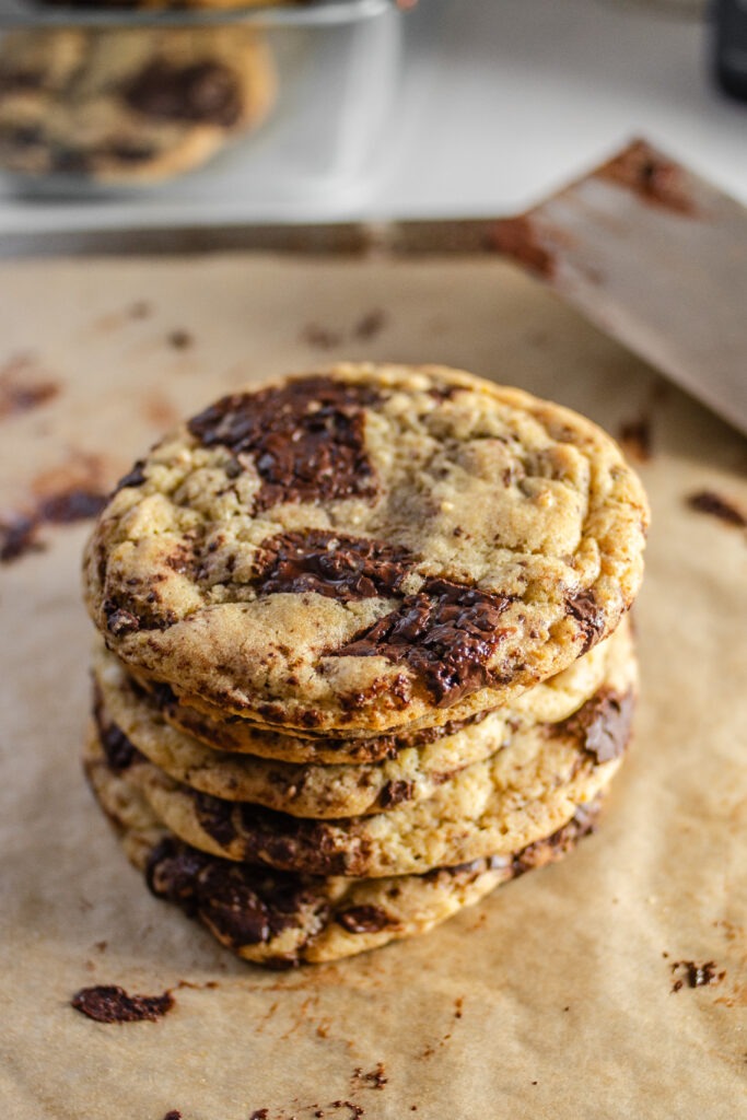 stack of chocolate chip sourdough cookies on a parchment lined baking sheet.