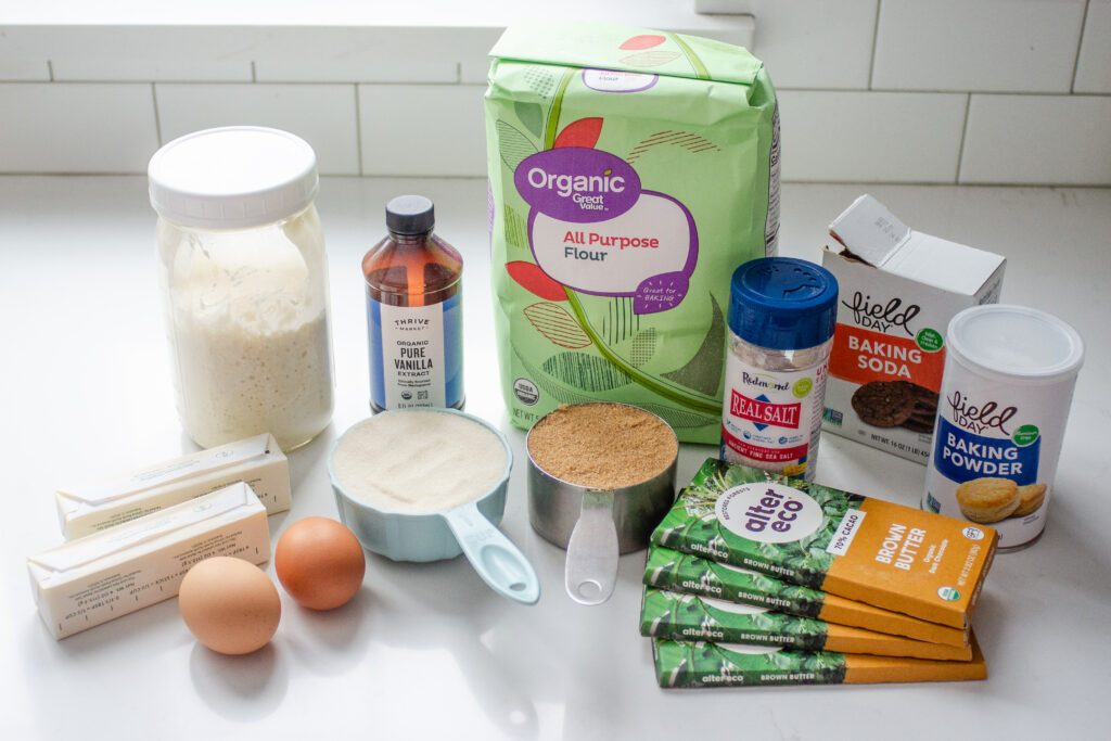 All of the ingredients needed to make chocolate chip sourdough cookies laid out on a white countertop.