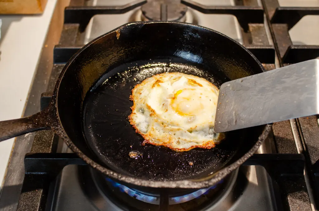 A crispy fried egg in a cast iron skillet on top of the stove.