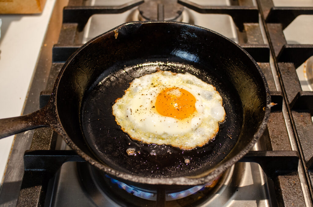 A crispy fried egg in a cast iron skillet on top of the stove.