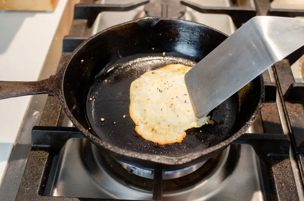 Poking the egg with a metal spatula to see if it's done.