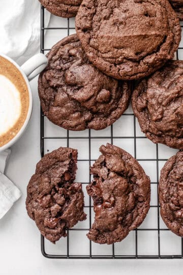 Chocolate espresso cookies on a wire rack with a latte off to the side.