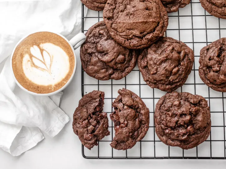 Chocolate espresso cookies on a wire rack with a latte off to the side.