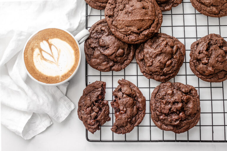 Chocolate espresso cookies on a wire rack with a latte off to the side.