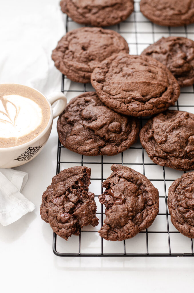 Chocolate espresso cookies on a wire rack with a latte off to the side.