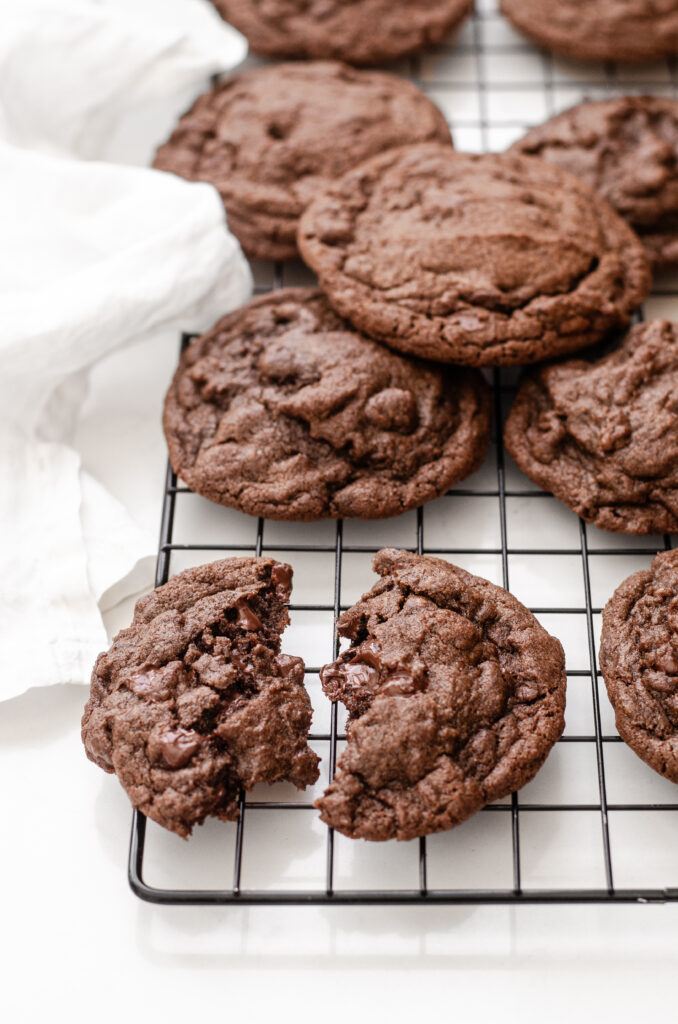 Chocolate espresso cookies on a wire cooling rack on a white countertop.