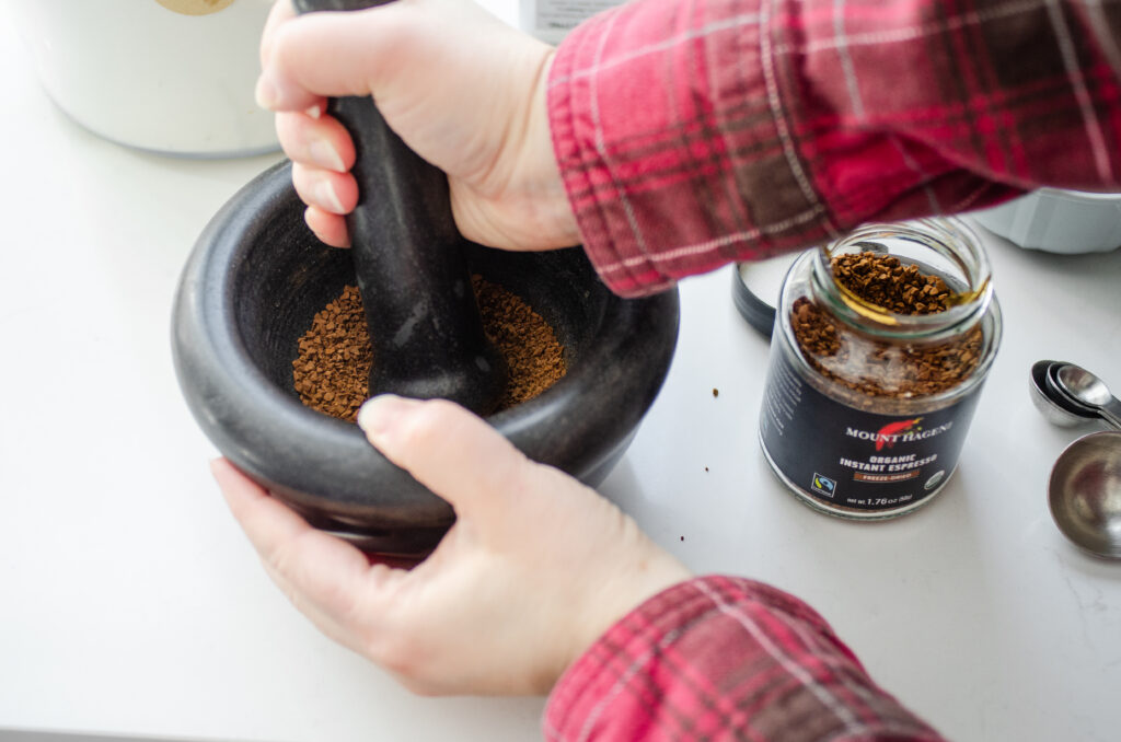 Grinding instant espresso into a powder using a mortar and pestle.