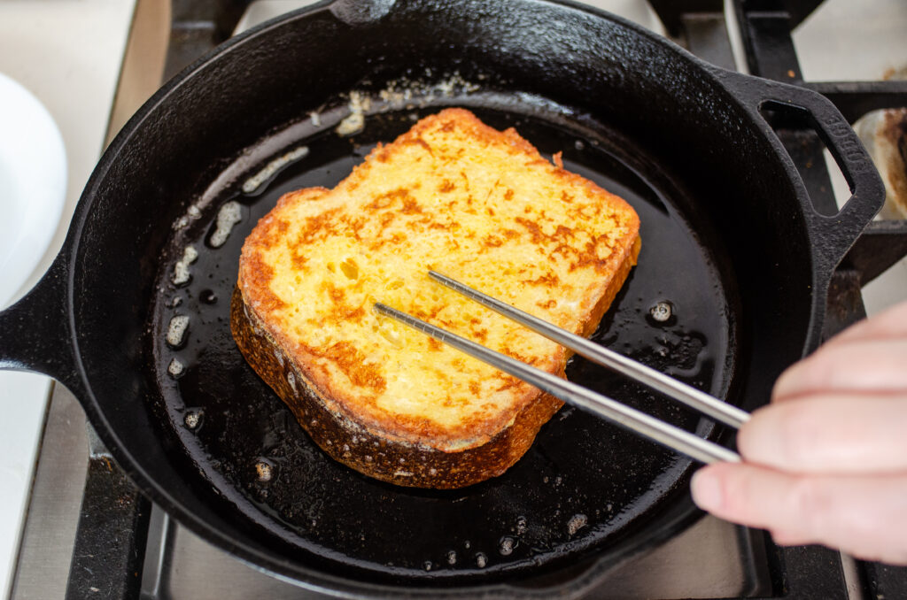 Poking a piece of French toast with chopsticks to see if it's done cooking.