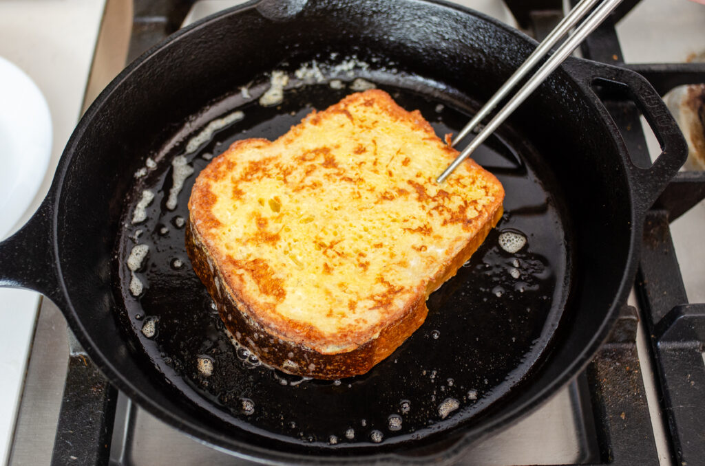 Flipping a piece of French toast with chopsticks.