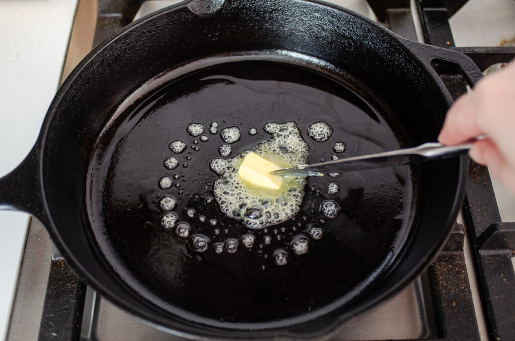 Adding butter to a cast iron skillet.