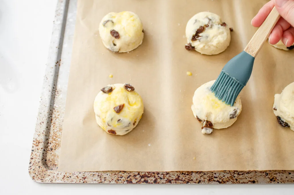 Brushing an egg wash on top the scones.