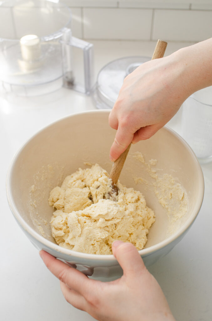 Gently mixing the dough with a wooden spoon.
