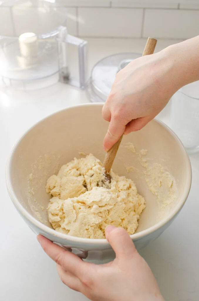 Gently mixing the dough with a wooden spoon.