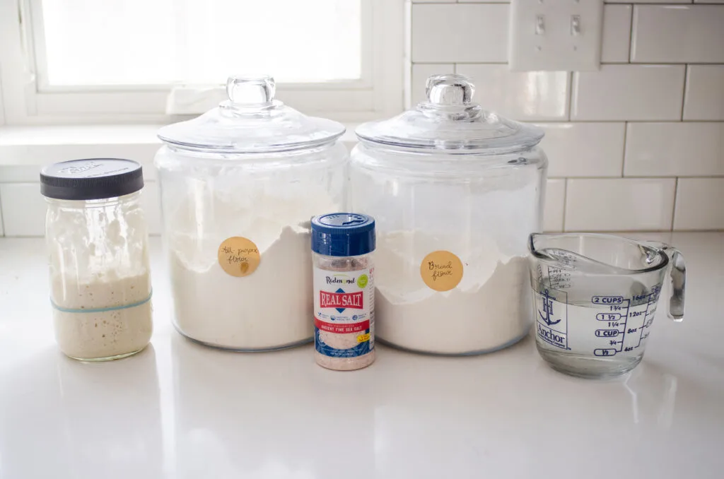 All of the ingredients needed to make a loaf of sourdough bread in a Dutch oven.