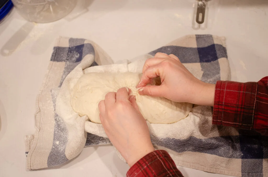 Stitching the loaf of sourdough bread after it's placed in the banneton basket.