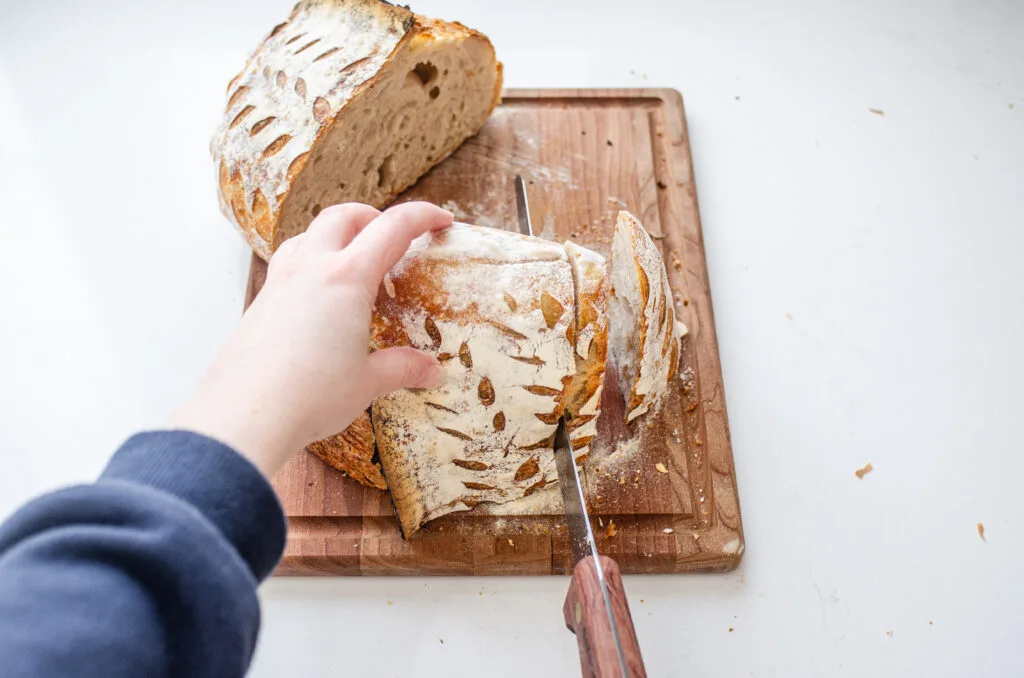 A top down shot showing the best way to slice a loaf of artisan sourdough bread.