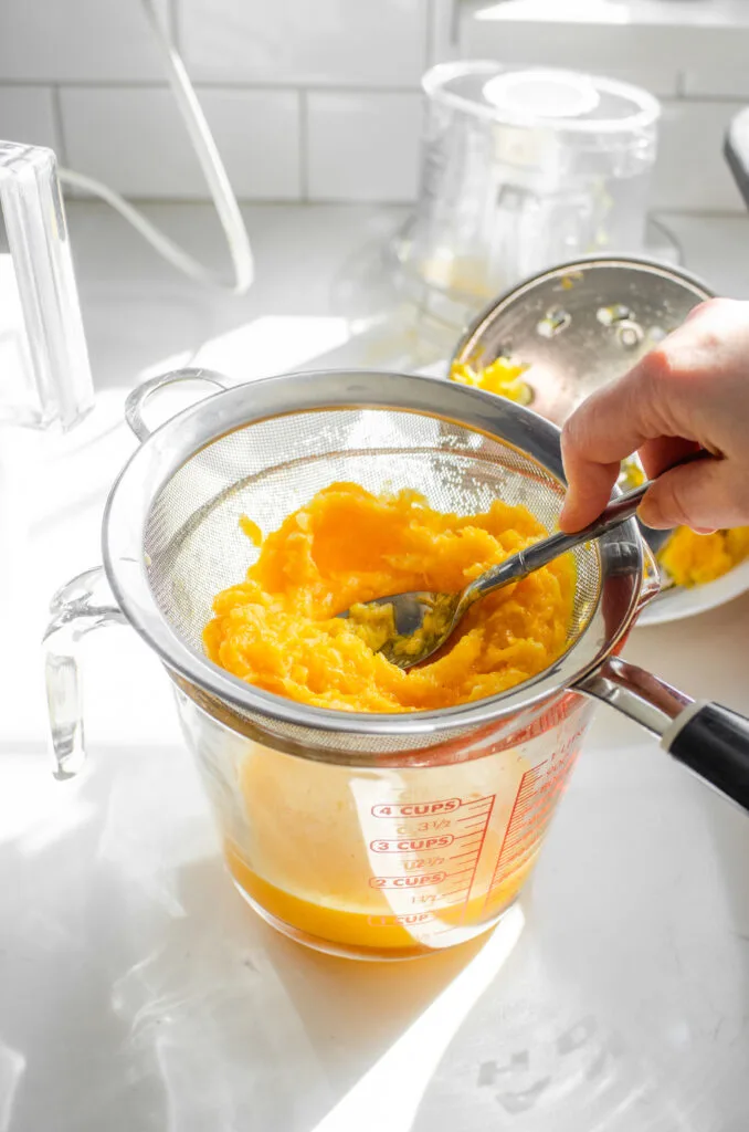 Pressing the pulp with a spoon to extract more juice.