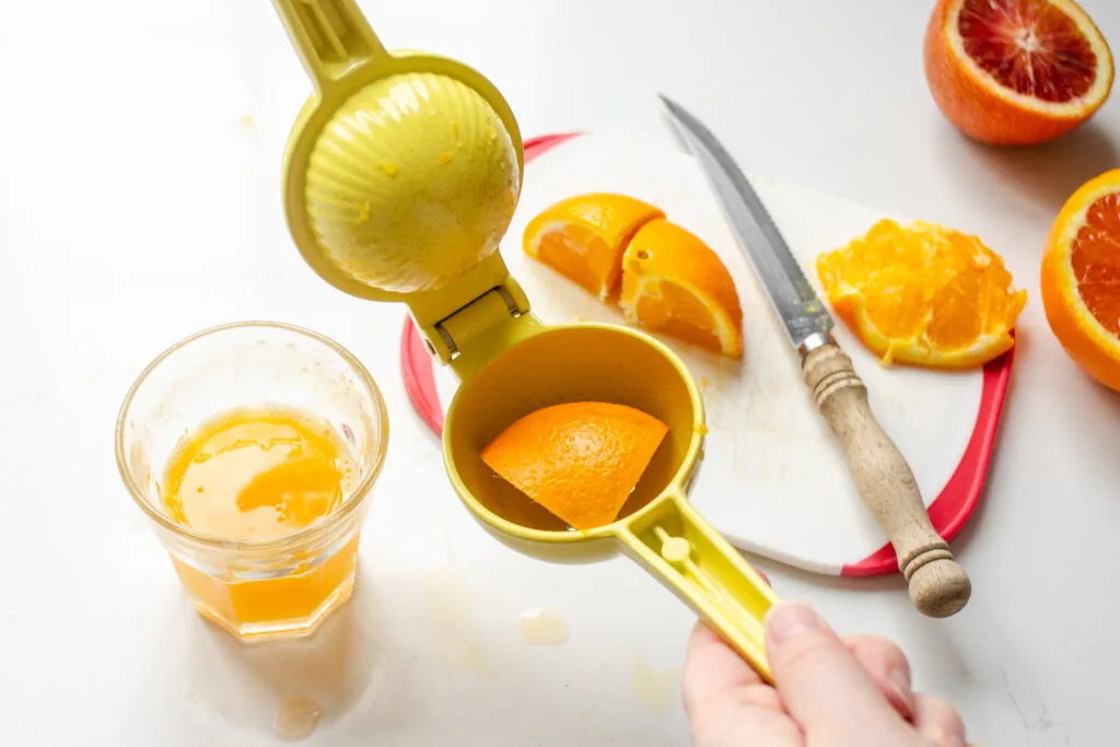 Cutting an orange into smaller pieces to fit into a citrus press.