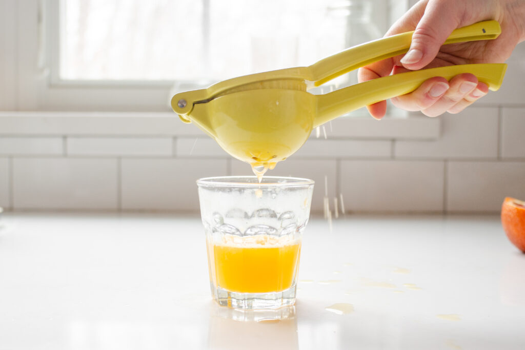 Using a yellow citrus press to squeeze fresh juice into a glass.