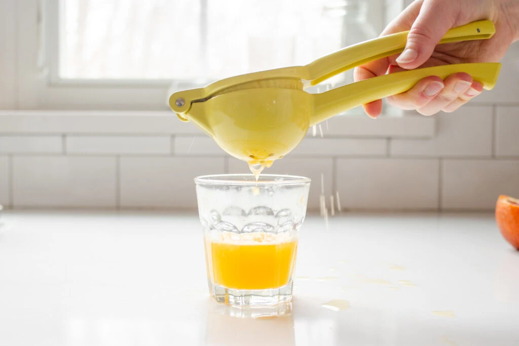 Using a yellow citrus press to squeeze fresh juice into a glass.