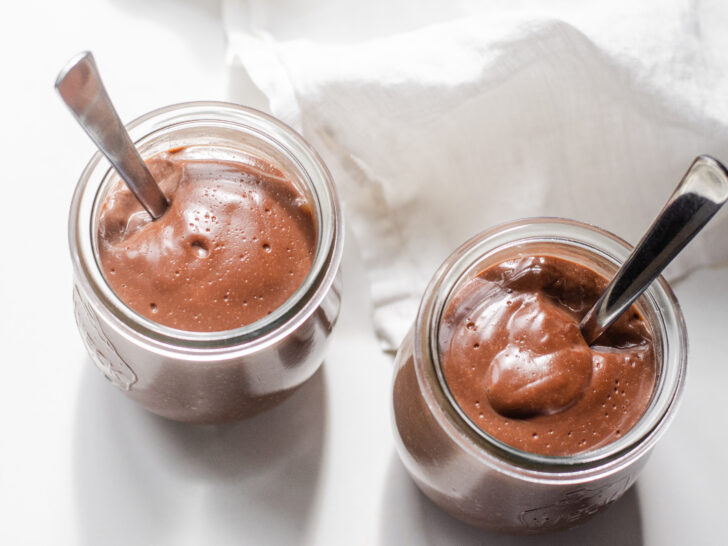 Two jars of homemade chocolate pudding from a top down view.
