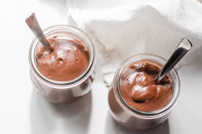 Two jars of homemade chocolate pudding from a top down view.