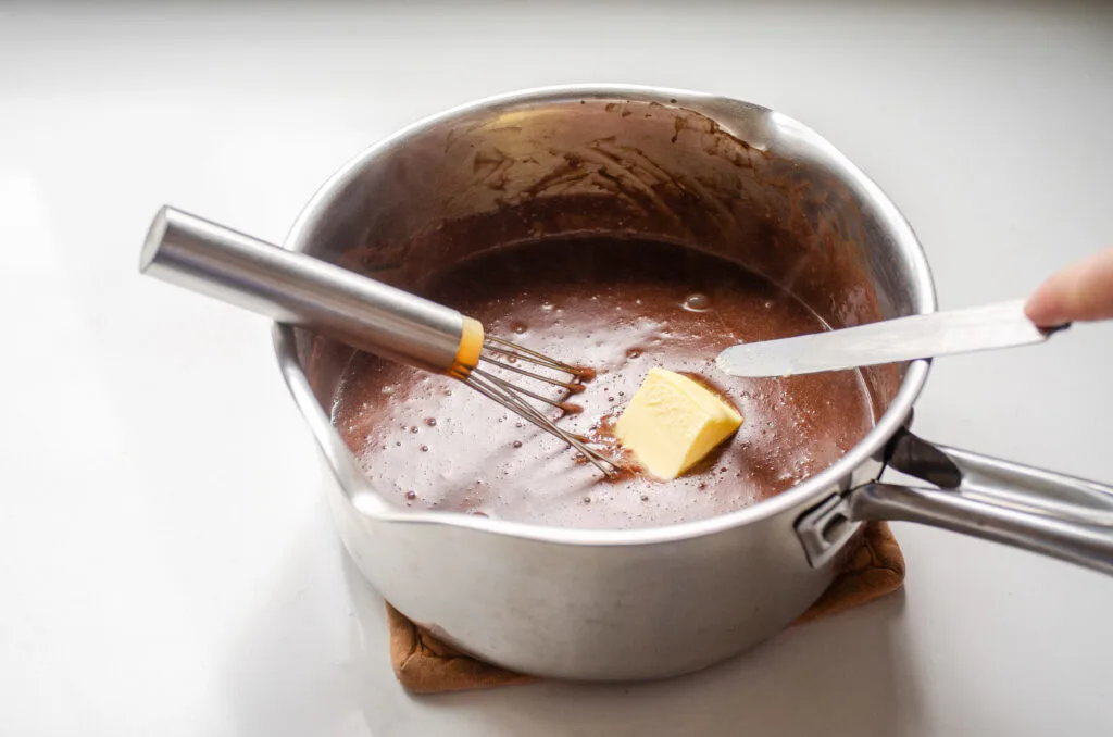 Adding the butter to the pudding off the stove.