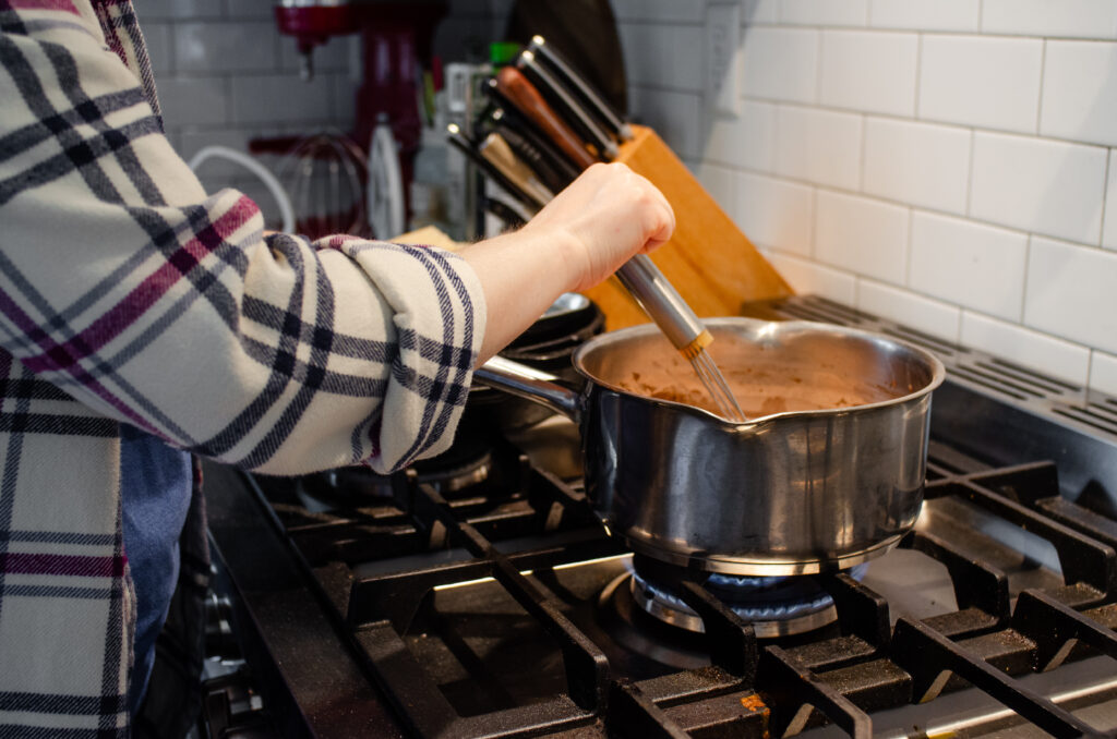 Whisking the pudding on the stove while it cooks to prevent burning and lumps.