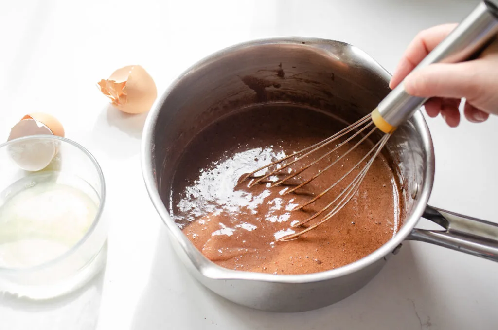 Whisking the dry ingredients with the yolks and milk to make a smooth paste.