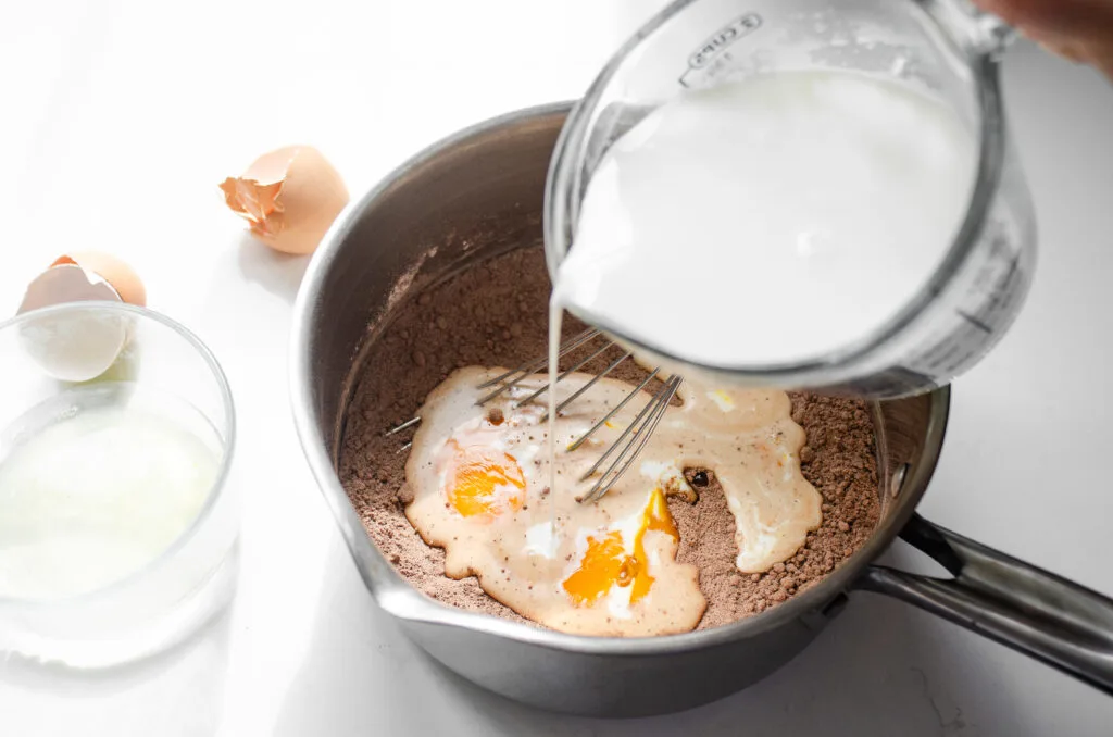 Pouring some of the milk over the dry ingredients and egg yolks.
