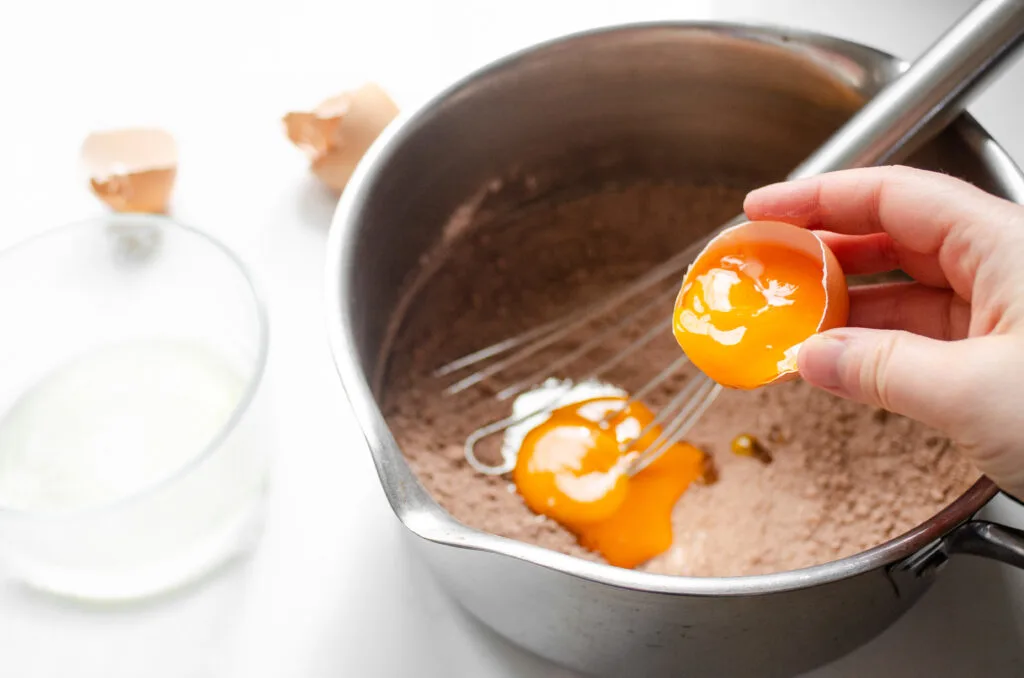 Adding the egg yolks to the dry ingredients in the saucepan.