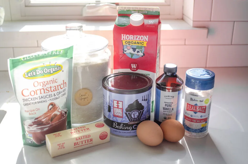 All of the ingredients needed to make chocolate pudding laid out on a sunny countertop.