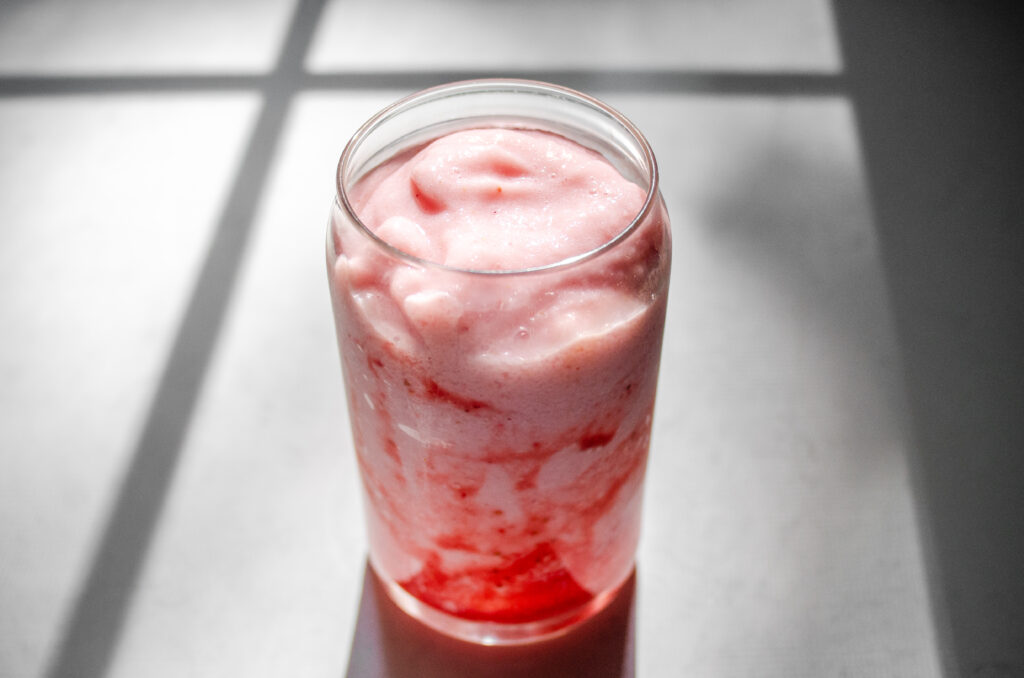 A strawberry frappuccino on a sunny countertop.