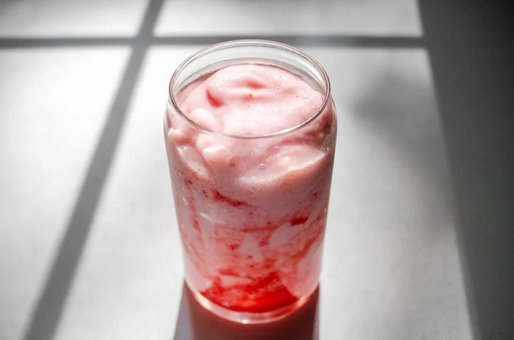 A strawberry frappuccino on a sunny countertop.