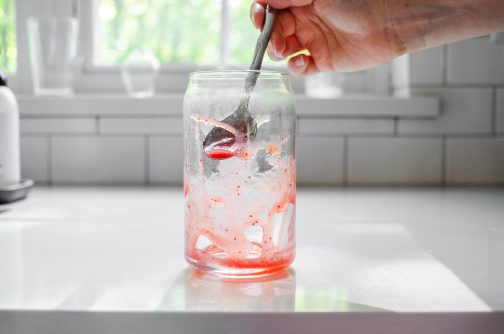 Drizzling strawberry puree into a glass.