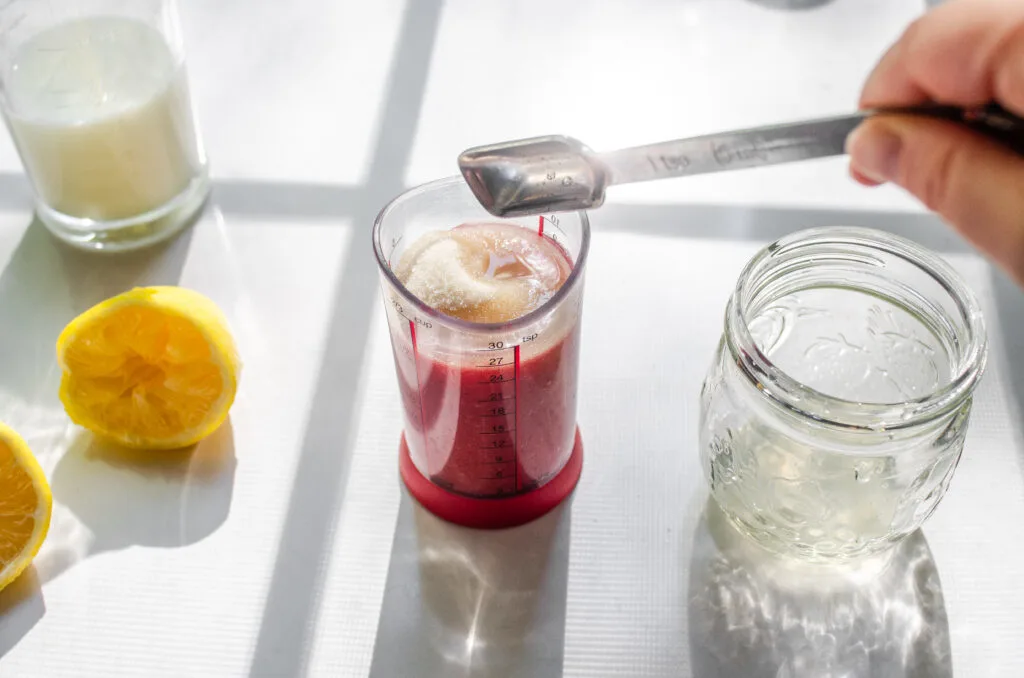 Adding lemon juice and sugar to the strawberry puree.