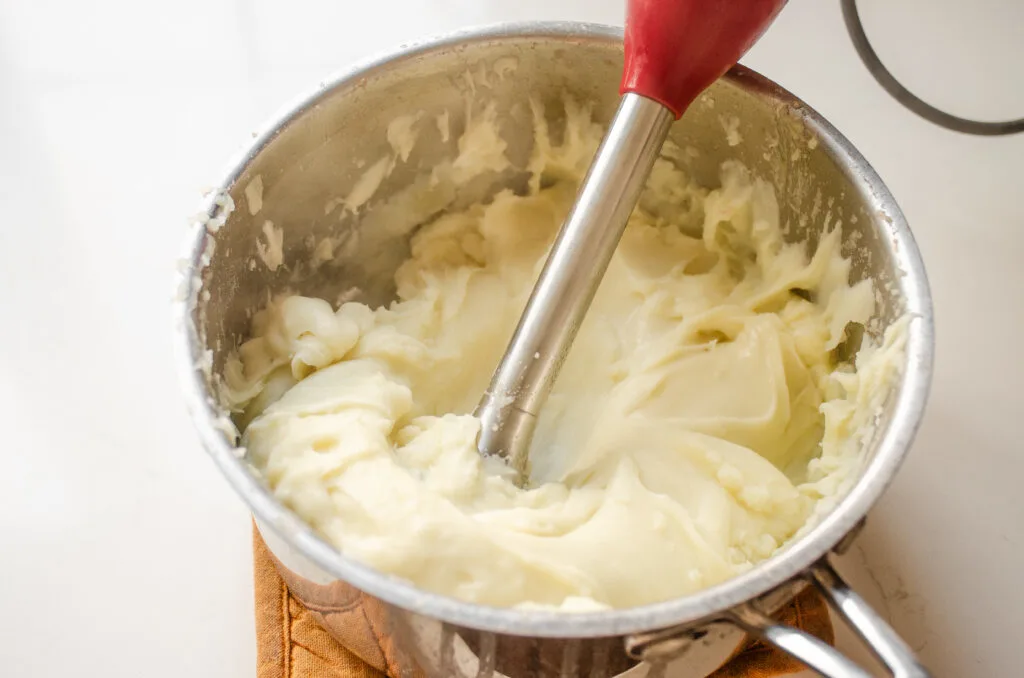 A close up shot of potatoes mashed with an immersion blender.