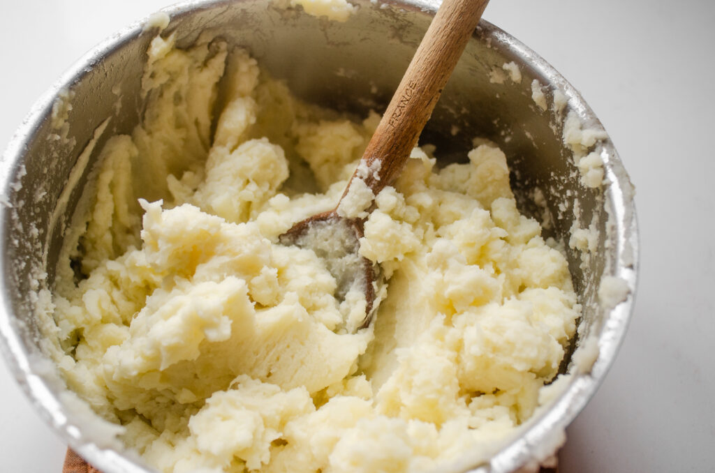 A close up photo of potatoes that were mashed with a spoon.