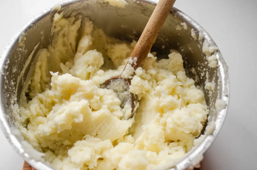 A close up photo of potatoes that were mashed with a spoon.