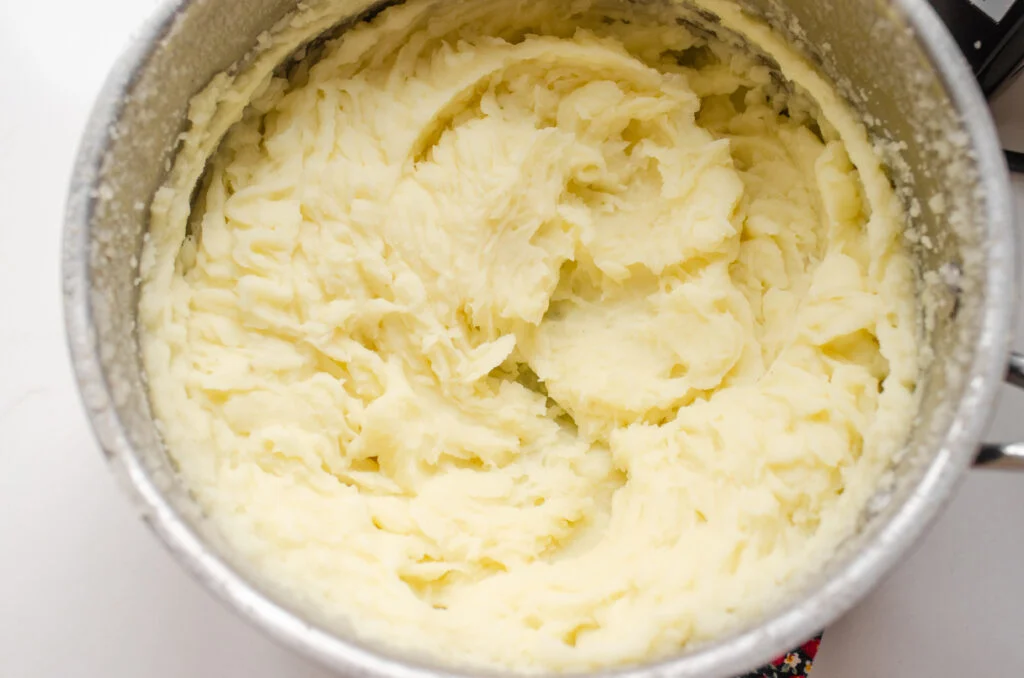 Close up shot of potatoes mashed with an electric hand mixer.
