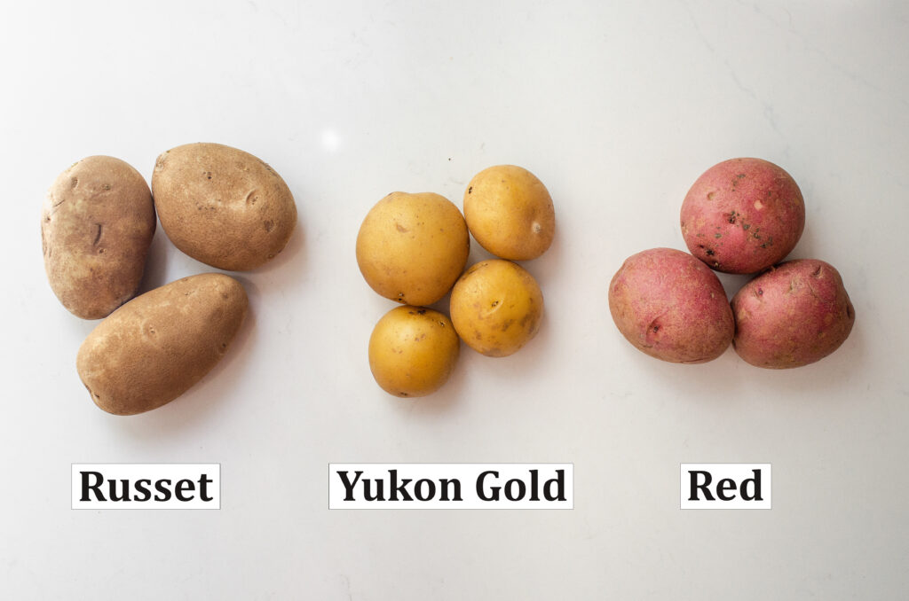 3 common types of potatoes on a white countertop with words to label each kind.