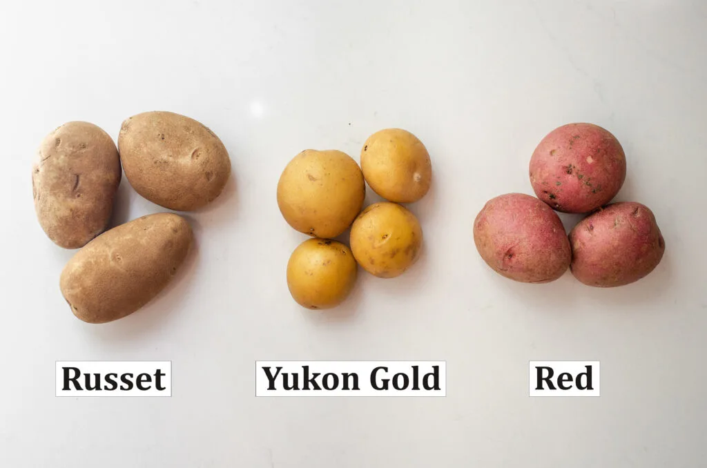 3 common types of potatoes on a white countertop with words to label each kind.