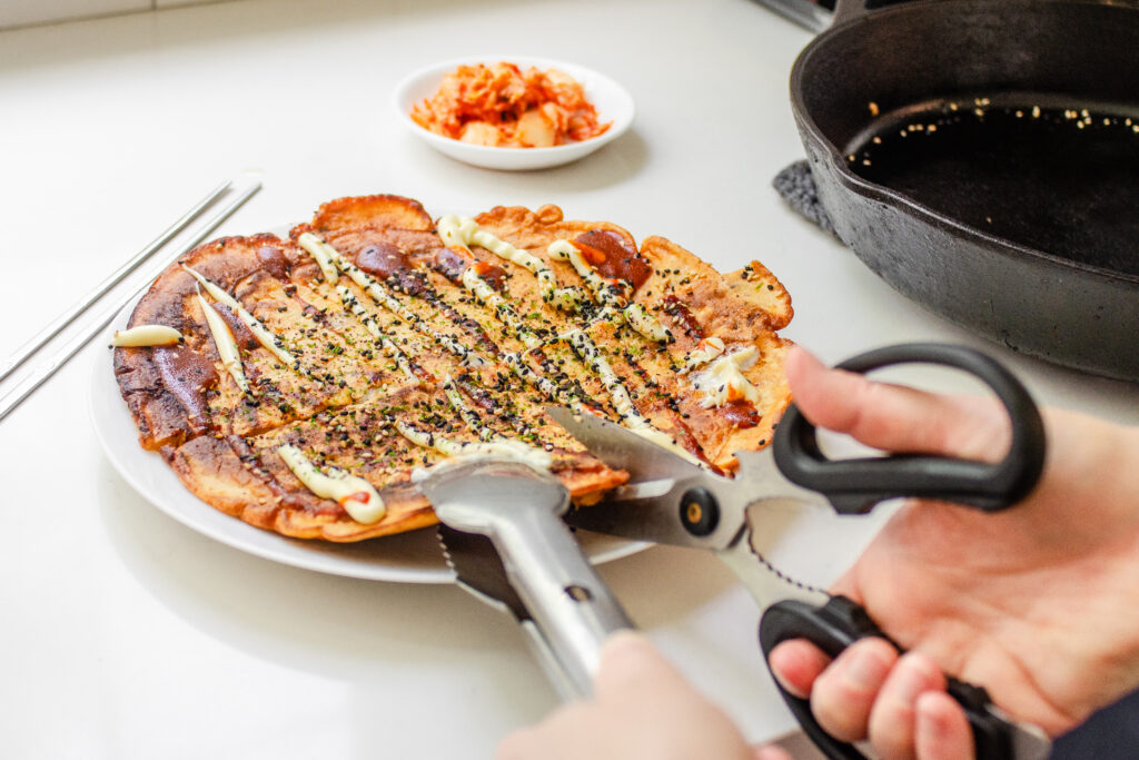 Cutting the sourdough discard kimchi pancake with scissors. 