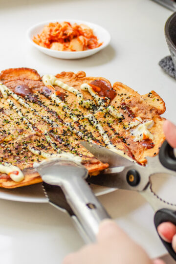 Cutting the sourdough discard kimchi pancake with scissors.