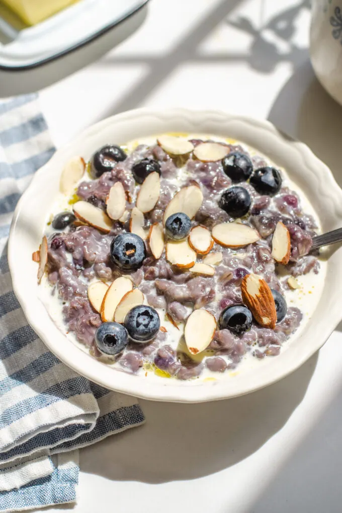 A bowl of blueberry oatmeal with fresh blueberries and sliced almonds on top.