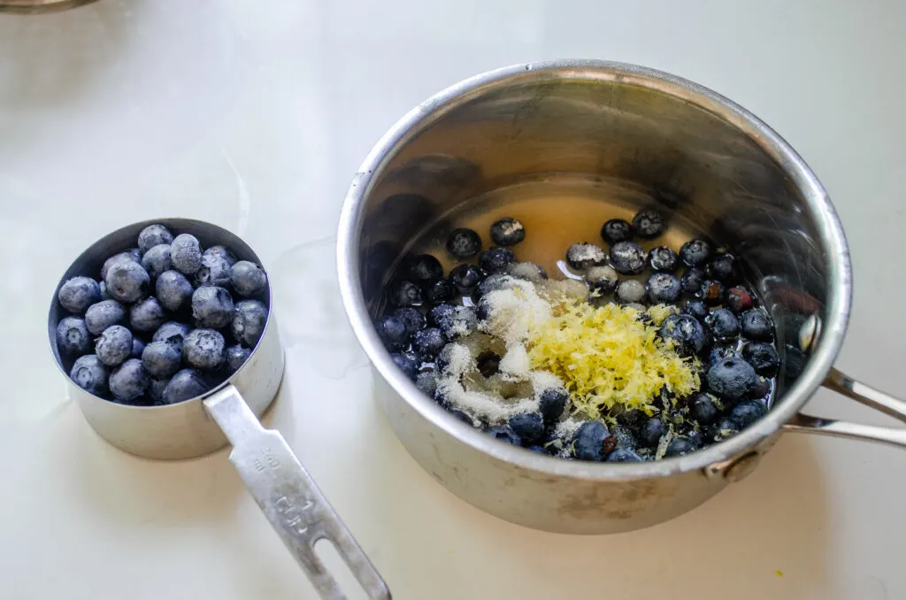 Measuring all of the ingredients except for 1 cup of blueberries into the saucepan.